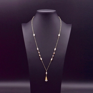 Elegant baroque pearl long necklace on a black bust display with golden wire pendant