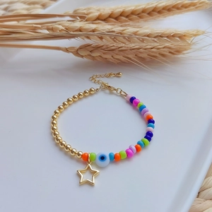 Detail of 18K gold-plated beaded bracelet with evil eye and hollow star charms