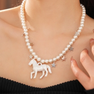 Detail of white pearl necklace featuring silver star charms and a large horse pendant
