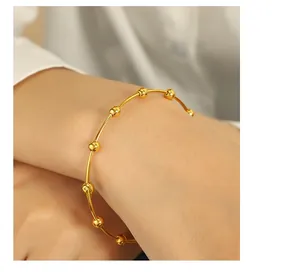 Detailed view of a minimalist gold stainless steel bracelet with small beads on a female wrist