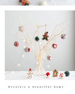 Close-up of wool felt ornaments and wooden snowflakes hanging on white Christmas branches