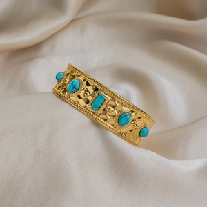 Detail eines vergoldeten 18K Manschettenarmbands mit Türkissteinen auf Seide