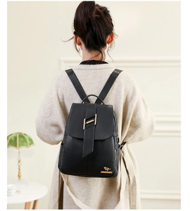 Detail of black pebbled leather backpack featuring golden hardware and H-buckle closure