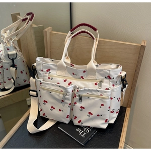 Detail of printed canvas tote bag with cherry pattern and adjustable shoulder strap