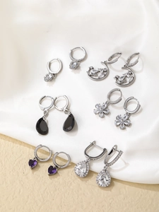 Vue détaillée de boucles d'oreilles cœur en argent et pendentifs sur fond de soie