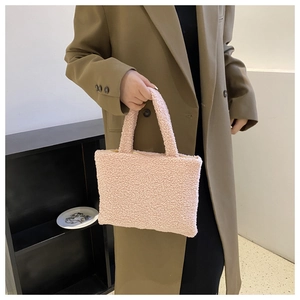 Detailed close-up of a stylish pink plush handbag being carried by a model