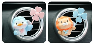 Detailed view of cute penguin and lion cartoon car air vent freshener clips on dashboard