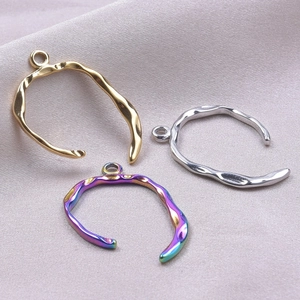 Irregular C-shaped stainless steel charms in gold and silver on purple silk background
