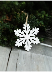 White wooden snowflake ornament hanging on a pine branch for Christmas decor