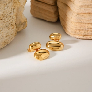 Orecchini a perno ovali minimalisti placcati oro 18k esposti su una pietra naturale