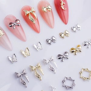 Detailed view of 3D metal alloy nail charms featuring gold bows and rhinestone accents