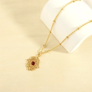 Detail of 18K gold plated vintage necklace with red gemstone and hollow floral pendant