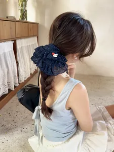 Detailed view of oversized dark blue polka dot scrunchie with ruffled edges on hair