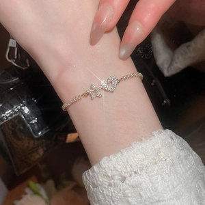 Close-up of gold heart and star bracelet with pave zircons on wrist with star flare