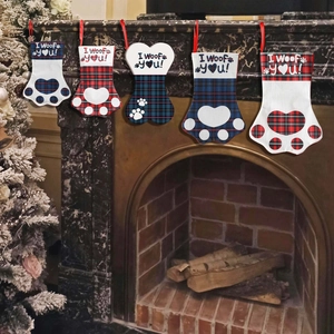 Plaid Christmas stockings with dog paw and bone shapes hanging on a festive fireplace