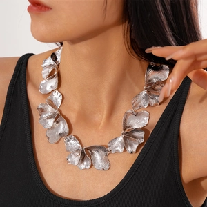 Detail showing textured silver metal flower petals on a statement necklace worn by a model