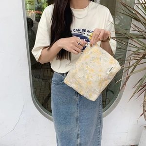 Close-up of floral embroidery on beige portable makeup bag with zipper closure