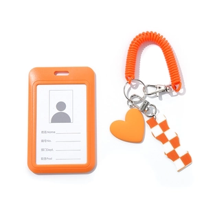 Detailed view of orange ID card holder with heart charm and checkerboard wristlet strap
