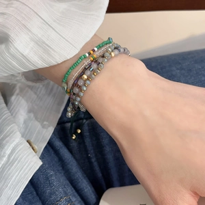 Close-up of Bohemian layered beaded bracelets with green and white crystals on wrist