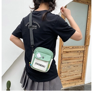 Detailed view of green and white canvas messenger bag worn by model in a casual style