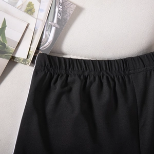 Detail of black sports shorts featuring elastic waistband and white side stripe trim
