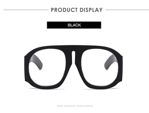 Detail of oversized black thick-frame sunglasses with integrated nose pads and wide temples