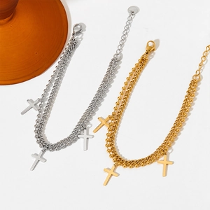 Gold and silver double-layer cross pendant bracelets on white surface with tray detail