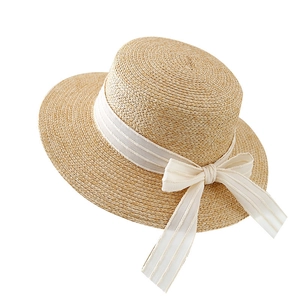 Handwoven straw sun hat with white ribbon bow in classic French vintage style