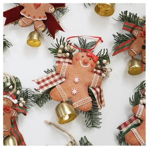 Flat lay of Christmas gingerbread man ornaments with red velvet bows and golden bells