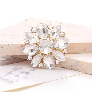 Macro shot of marquise crystal flower accessory with gold base on a beige stone