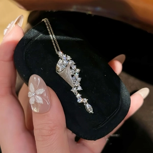 Elegant hourglass pendant necklace with sparkling zircons displayed on a black velvet box