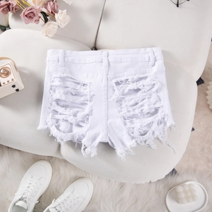 Detail of white distressed denim shorts with frayed ripped holes and floral background