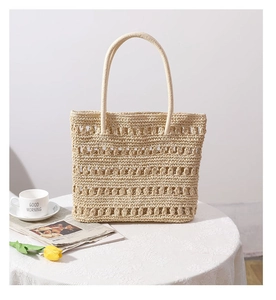 Hollow straw tote bag on lace tablecloth with tulip and coffee for beach vacation