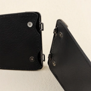 Detail of black leather corset belt showing dark grey metal buckle and screw fixings