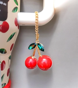 Detail of red cherry charm with rhinestone leaves and gold chain on a tumbler
