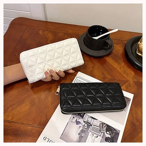 Quilted long wallets for women in black and white leather on a wooden cafe table