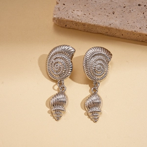 Silver nautilus shell drop earrings with textured metal finish on a minimalist stone base