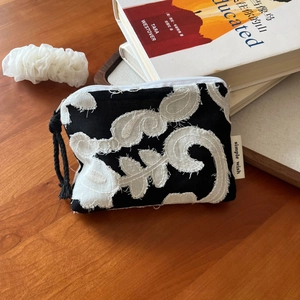 Detail of bohemian linen mini pouch with white vine embroidery and black woven strap