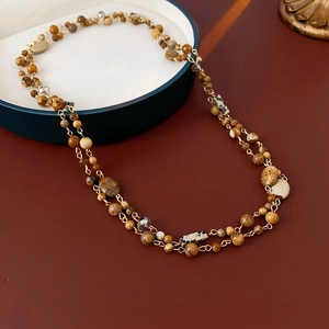 Close-up of bohemian layered necklace with brown earth-tone stone beads and gold chain