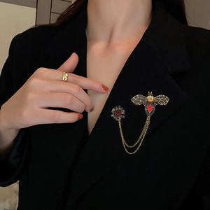 Vintage gold bee brooch with red gemstone and double chains on dark blazer