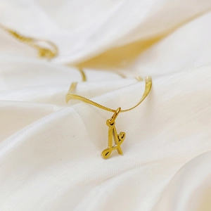 Detail of gold letter A pendant with heart cutout on elegant snake chain necklace