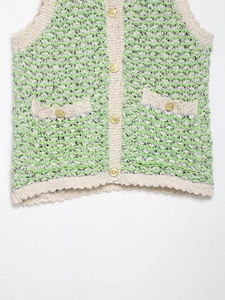 Detailed close-up of textured knit fabric with golden crest buttons on a green vest
