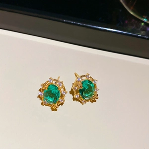 Detailed close-up of 18k gold plated stud earrings with green oval zircon and diamonds