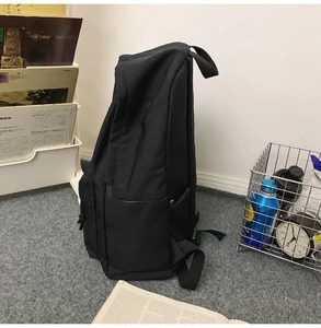 Side view of a large black minimalist nylon backpack showing depth and side pocket design