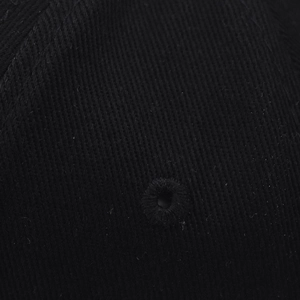 Vue macro montrant l'oeillet brodé et la texture sergée d'une casquette de baseball noire