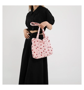 Detail of pink corduroy tote bag featuring red strawberry patterns and side pockets