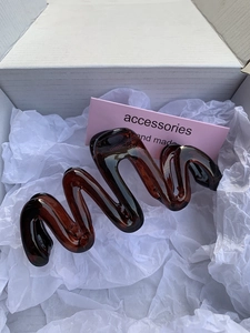 Detail view of large amber wavy hair claw clip made of glossy translucent resin material