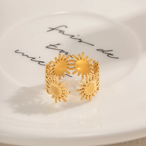 Close-up of 18k gold plated sunflower ring with sunburst pattern on white ceramic dish