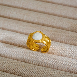 Dettaglio macro dell'anello martellato dorato con intarsio in smalto bianco in stile retrò