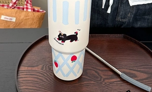 Detail of white tumbler with cartoon cat illustration and a reusable stainless steel straw